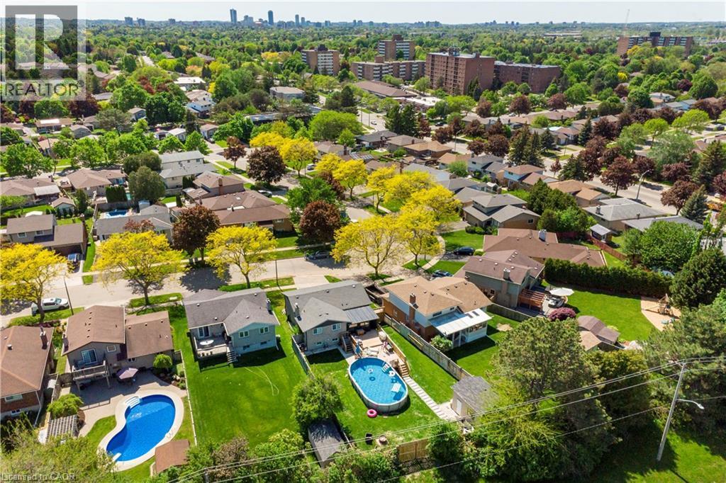 Aerial perspective showcasing a residential neighborhood with established homes, mature trees, and a distant cityscape - 44 Oakhurst Crescent, Kitchener, ON - Outdoor With In Ground Pool With View