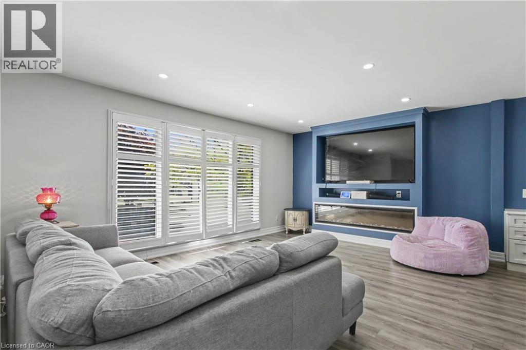 Living area featuring a custom built-in entertainment center, recessed lighting, and wood-finish flooring - 44 Oakhurst Crescent, Kitchener, ON - Indoor Photo Showing Living Room