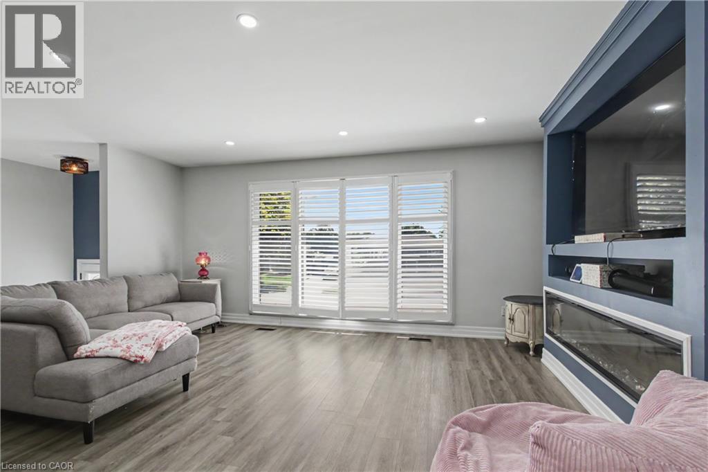 Spacious living area featuring wood-finish flooring, recessed lighting, and a prominent built-in media center with an integrated linear fireplace - 44 Oakhurst Crescent, Kitchener, ON - Indoor Photo Showing Living Room With Fireplace