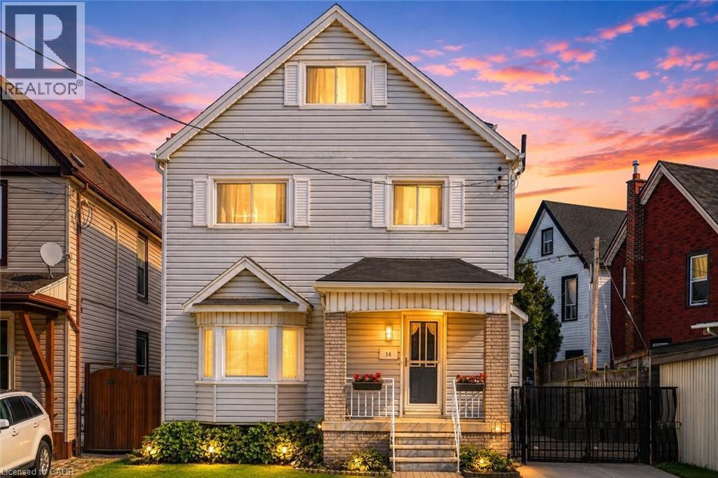 Two-story residence featuring light-colored horizontal siding and a prominent gabled roofline - 14 Niagara Street, Hamilton, ON