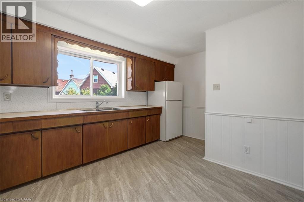 Kitchen featuring a double basin sink, ample wood cabinetry, light-toned countertops, and wood-finish flooring - 14 Niagara Street, Hamilton, ON