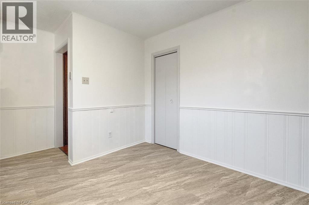 Room featuring wood-finish flooring, white wainscoting, and a neutral wall palette - 14 Niagara Street, Hamilton, ON