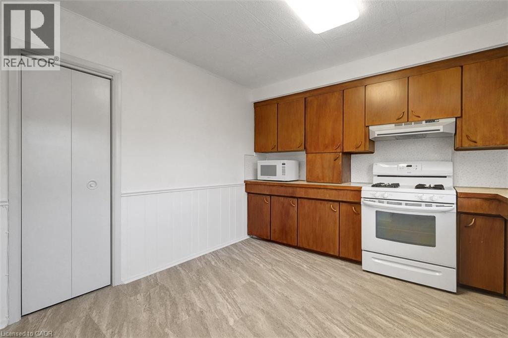 Kitchen featuring wood cabinetry, white gas range, and wood-finish flooring - 14 Niagara Street, Hamilton, ON