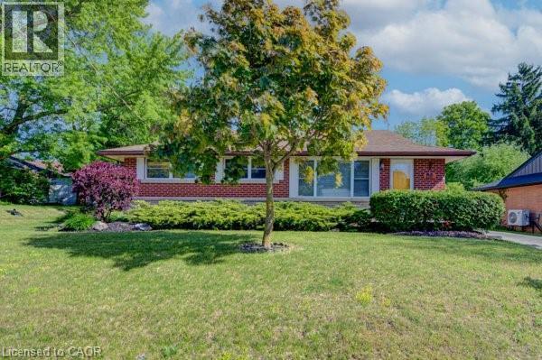 Traditional brick residence featuring a prominent front lawn, established landscaping, and a pitched roof - 251 Union Street E, Waterloo, ON