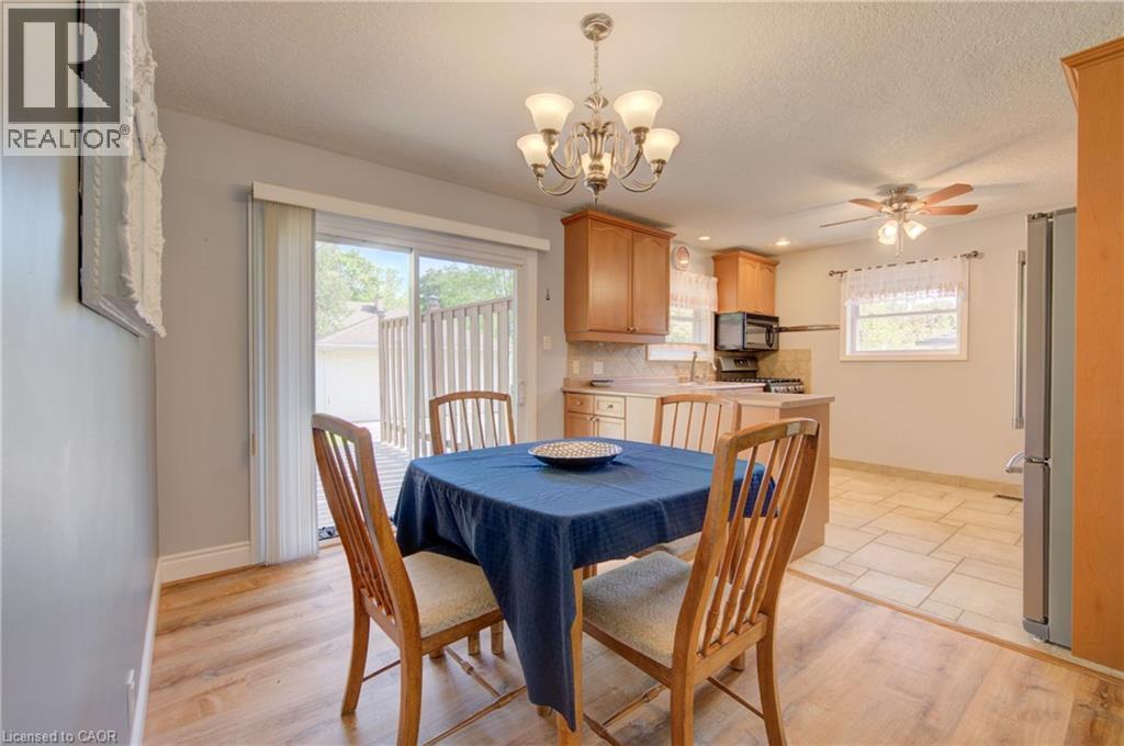 Dining area featuring wood-finish flooring, a contemporary chandelier, and direct access to an outdoor deck via sliding glass doors - 251 Union Street E, Waterloo, ON