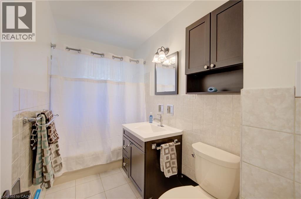 Bathroom featuring a dark wood-finish vanity with an integrated sink, a wall-mounted medicine cabinet, and a toilet - 251 Union Street E, Waterloo, ON