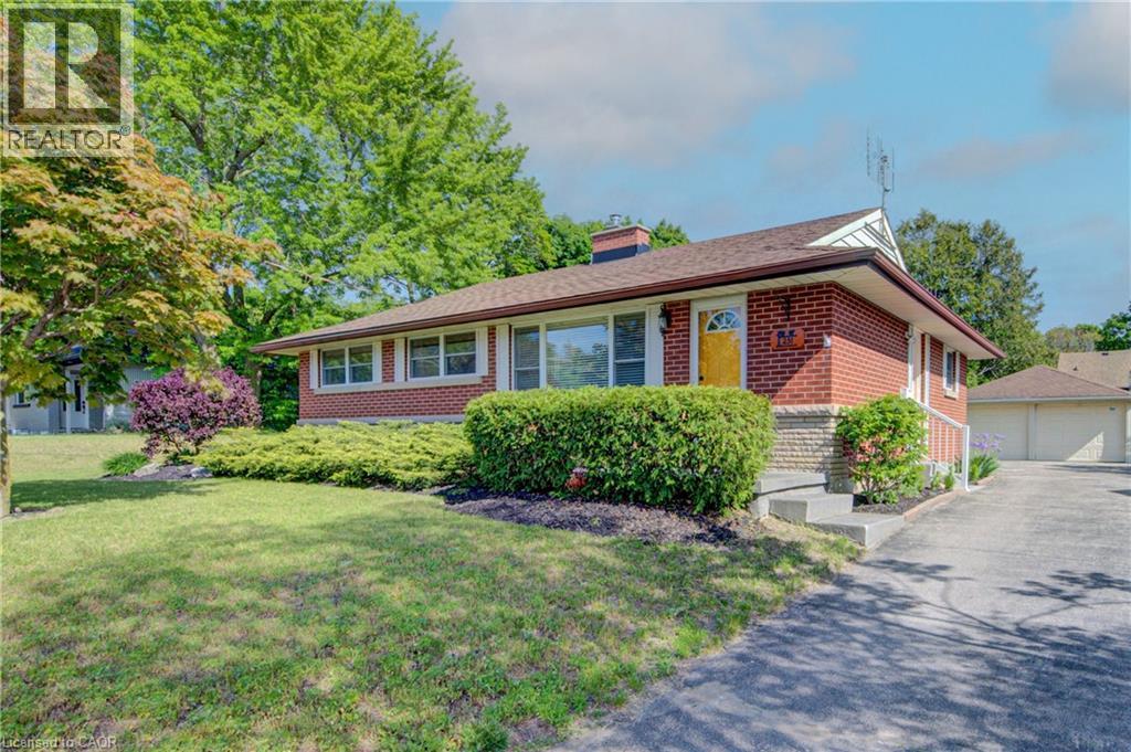 Brick exterior with stone accents, a deep brown shingle roof, a vibrant yellow front door, and a concrete driveway - 251 Union Street E, Waterloo, ON