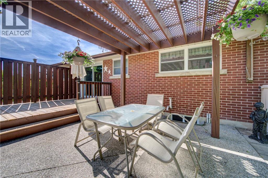 Outdoor living space featuring a wooden pergola, multi-level wood deck, privacy fencing, and a concrete patio - 251 Union Street E, Waterloo, ON