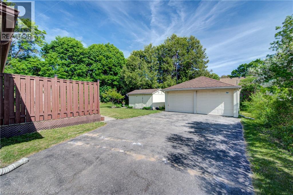 Two-car garage with multiple overhead doors, asphalt driveway, and a fenced yard - 251 Union Street E, Waterloo, ON