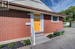 Brick exterior with contrasting yellow entry door, concrete steps, white handrail, and front-facing landscape bed -