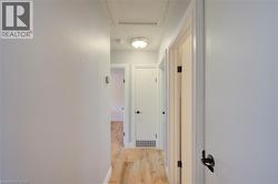 Hallway featuring wood-finish flooring, white walls, and white doors with matte black hardware -