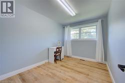 Bright room featuring light blue walls, wood-finish flooring, and white baseboards -