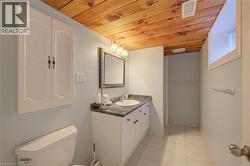 Bathroom featuring a wood-finish ceiling, light blue walls, white vanity with an integrated sink, dark countertop, and tiled flooring -