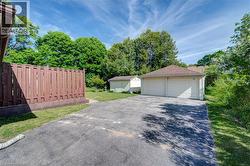 Two-car garage with multiple overhead doors, asphalt driveway, and a fenced yard -