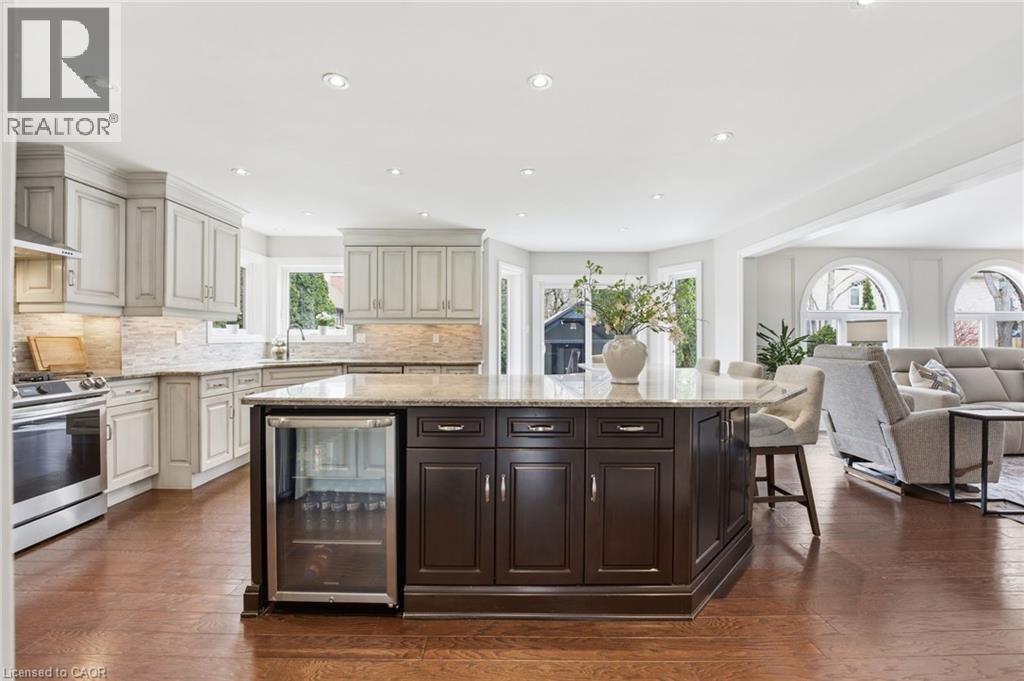 Kitchen with beverage cooler, light stone counters, a kitchen island, stainless steel range, and dual tone cabinets - 28 Deerview Avenue, Ancaster, ON