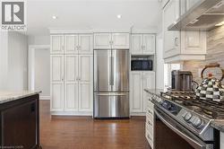 Kitchen featuring stainless steel appliances, light stone countertops, dark wood-style floors, recessed lighting, and backsplash -