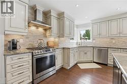 Kitchen featuring stainless steel appliances, light stone countertops, dark wood finished floors, recessed lighting, and decorative backsplash -
