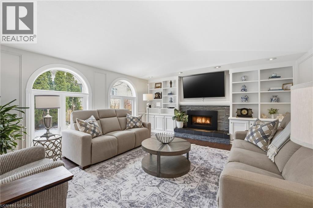 Living area featuring a fireplace, built in shelves, and wood finished floors - 28 Deerview Avenue, Ancaster, ON
