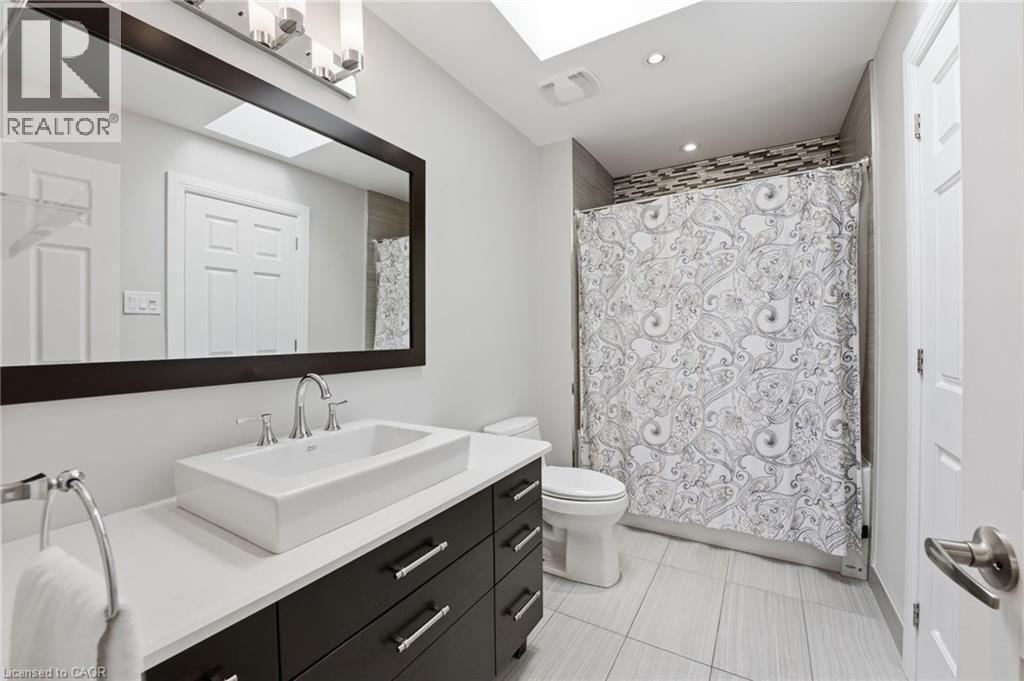 Bathroom with vanity, a skylight, shower / bath combo, and light tile patterned floors - 28 Deerview Avenue, Ancaster, ON