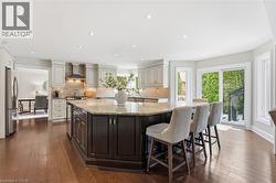 Dual tone kitchen featuring dark wood-style floors, a large island, light stone countertops, dual tone cabinets, and freestanding refrigerator -