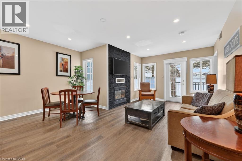 Living room with a multi sided fireplace, light wood finished floors, healthy amount of natural light, and recessed lighting - 90 Highland Drive Unit# 2014/15, Simcoe, ON