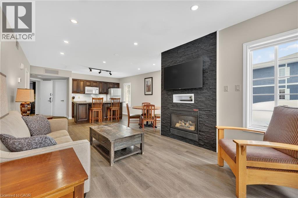 Living area featuring light wood-style floors, a stone fireplace, and track lighting - 90 Highland Drive Unit# 2014/15, Simcoe, ON