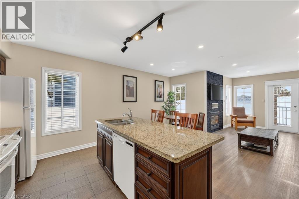 Kitchen with plenty of natural light, light stone counters, white appliances, rail lighting, and an island with sink - 90 Highland Drive Unit# 2014/15, Simcoe, ON
