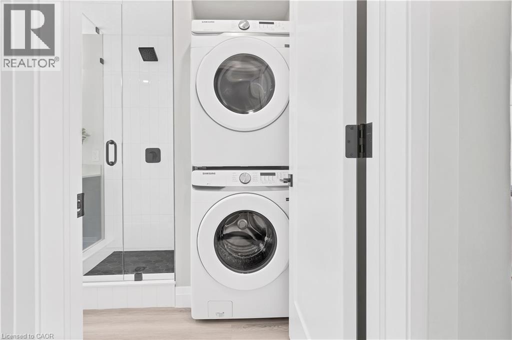 Stacked laundry appliances in a dedicated alcove, featuring a white finish and visible controls - 71 Blucher Street Unit# G, Kitchener, ON