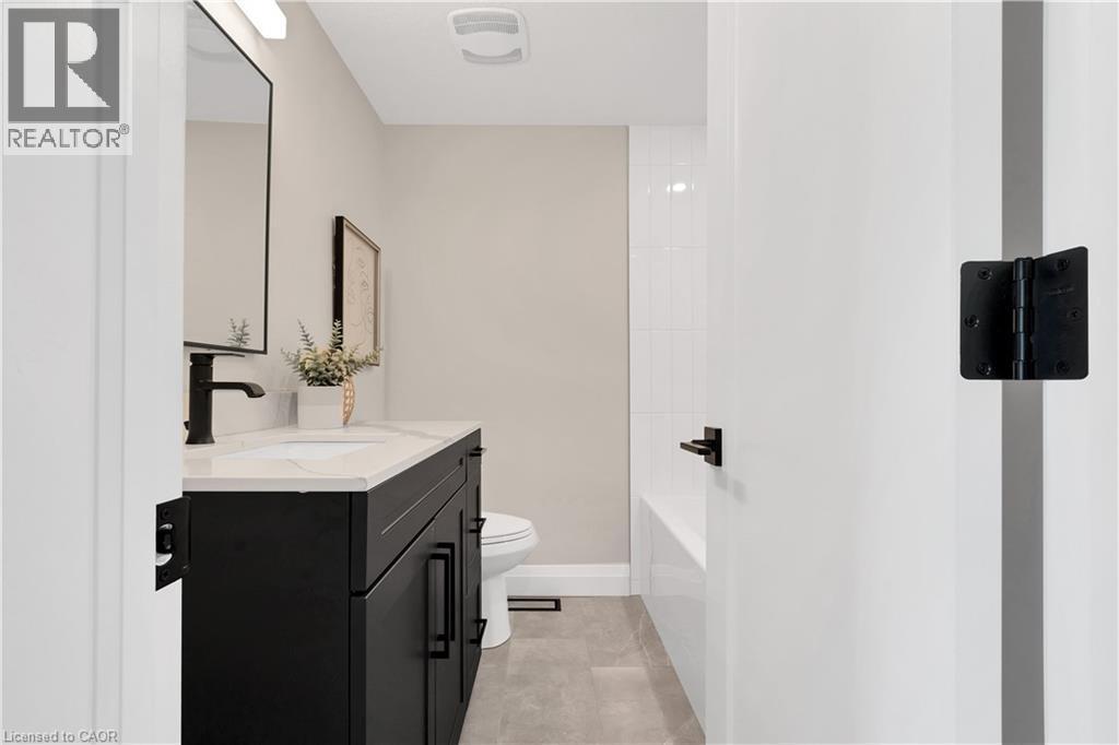 Bathroom featuring a dark wood vanity with a white countertop, undermount sink, and matte black faucet - 71 Blucher Street Unit# G, Kitchener, ON