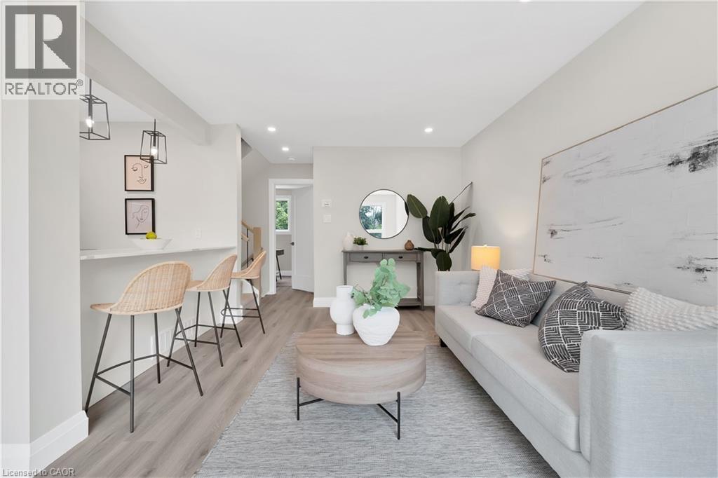 Open-concept living area featuring light wood-finish flooring, recessed lighting, and a white countertop breakfast bar with contemporary pendant lighting - 71 Blucher Street Unit# G, Kitchener, ON