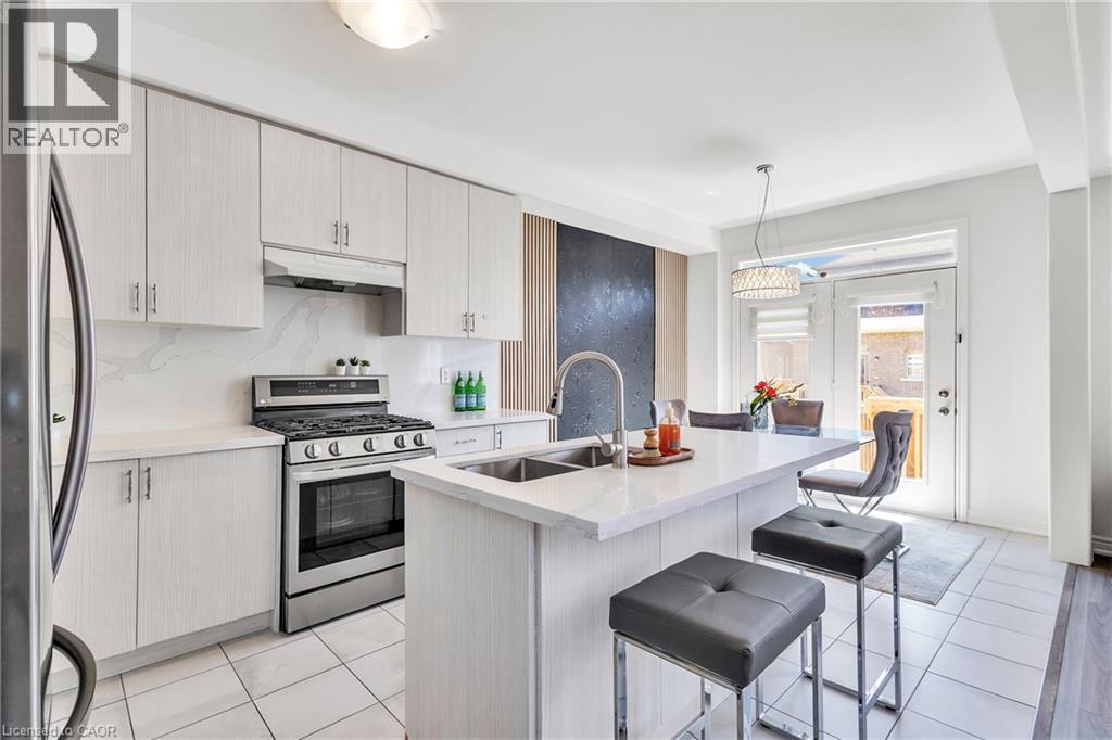 Contemporary kitchen featuring light wood-finish cabinetry, stainless steel appliances, and a central island with a sink - 101 Westfield Crescent, Waterdown, ON