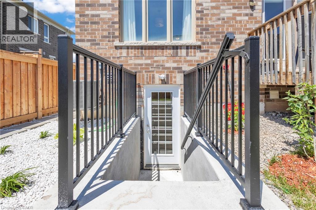 Exterior access door to the basement featuring an integrated glass panel and surrounding metal railings - 101 Westfield Crescent, Waterdown, ON