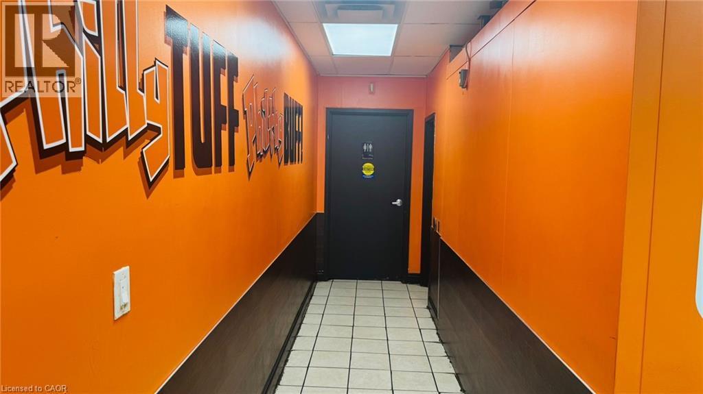 Hallway with two-tone orange and dark brown painted walls, white square floor tiles, and a black door - 2405 Fairview Street, Burlington, ON