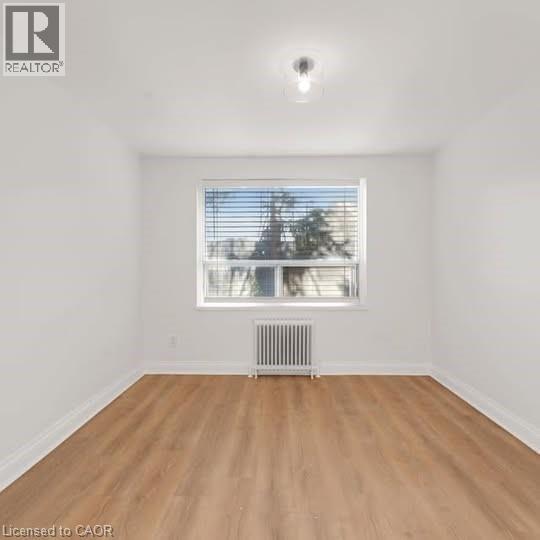 Bright room featuring wood-finish flooring and a large window with horizontal blinds - 57 Mericourt Road Unit# 111, Hamilton, ON - Indoor Photo Showing Other Room