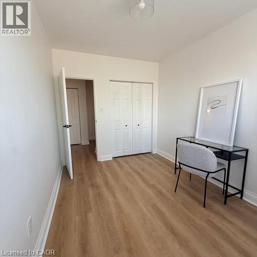 Bright interior space featuring wood-finish flooring, white walls, and a white bi-fold closet - 57 Mericourt Road Unit# 111, Hamilton, ON - Indoor Photo Showing Other Room