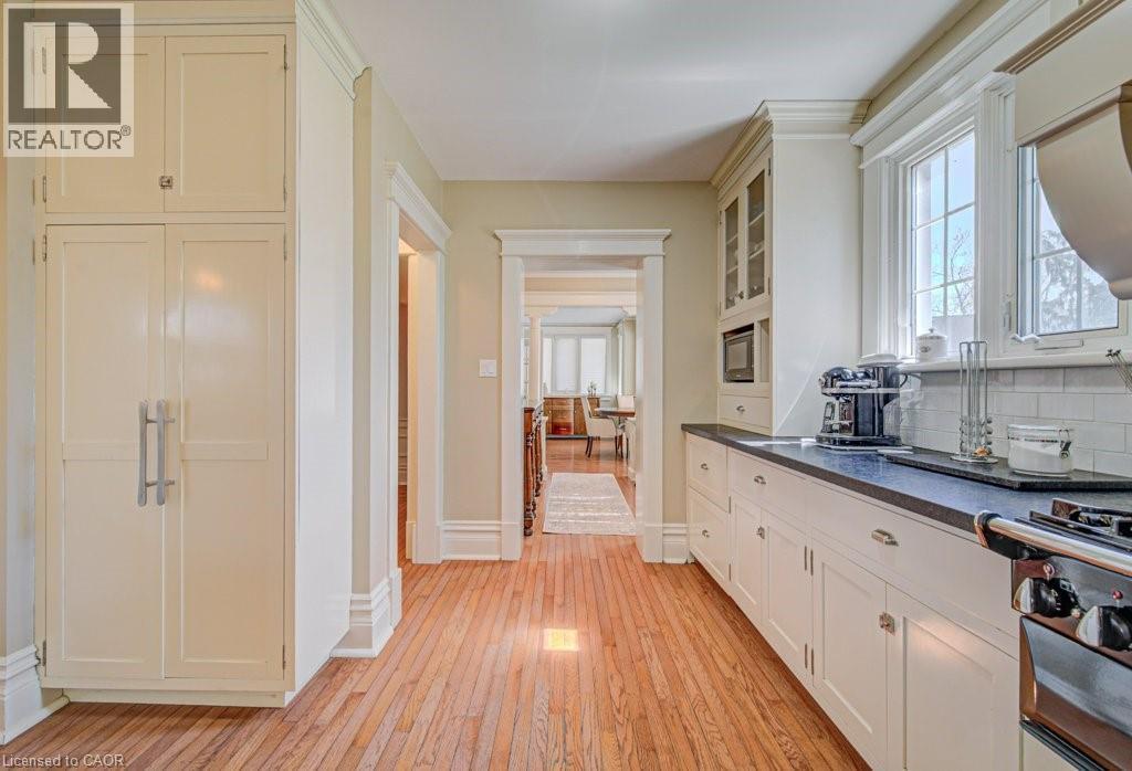 Kitchen featuring wood-finish flooring, cream-colored cabinetry, dark countertops, a subway tile backsplash, and a built-in microwave - 2032 Coronation Boulevard, Cambridge, ON - Indoor Photo Showing Other Room