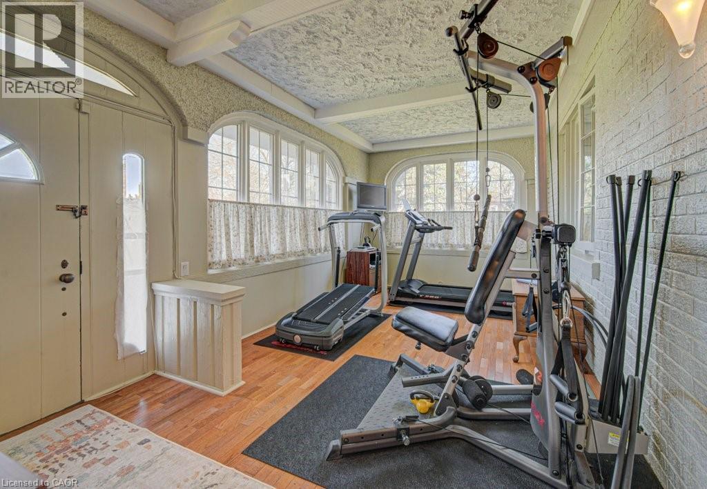 Interior space featuring wood-finish flooring, textured ceiling, arched windows, and a white paneled door with glass inserts - 2032 Coronation Boulevard, Cambridge, ON - Indoor Photo Showing Gym Room