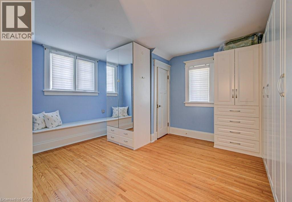 Hardwood flooring throughout this room featuring a built-in window bench with storage, two windows with blinds, a mirrored cabinet, and an additional built-in storage unit with drawers and upper cabin - 2032 Coronation Boulevard, Cambridge, ON - Indoor Photo Showing Other Room