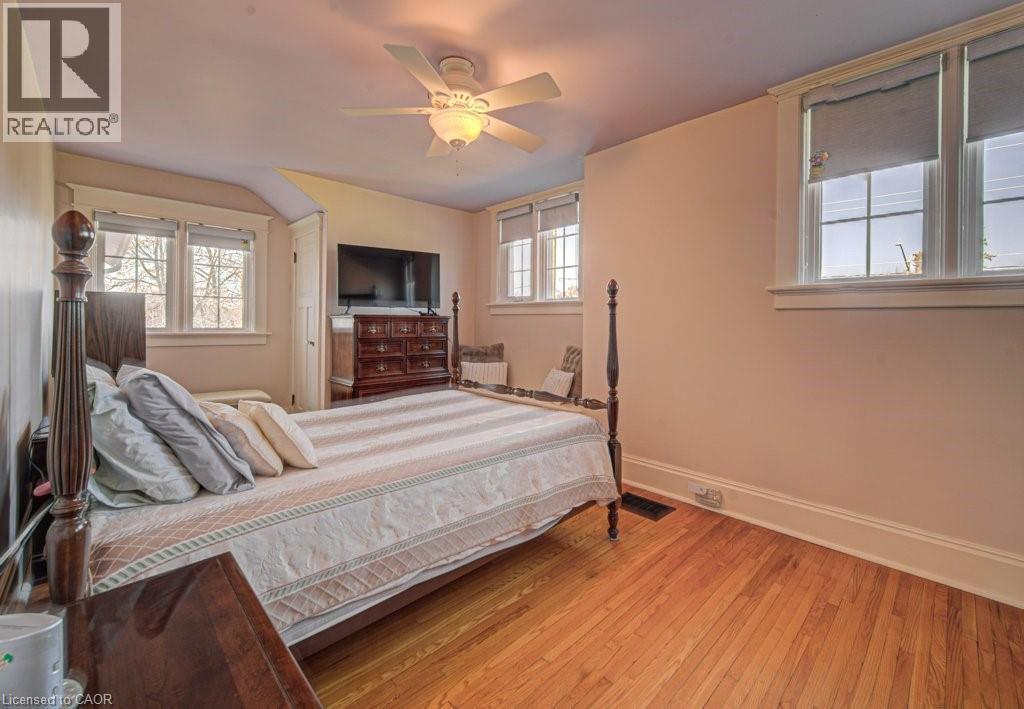Hardwood flooring throughout featuring multiple windows with white trim and a ceiling fan with integrated lighting - 2032 Coronation Boulevard, Cambridge, ON - Indoor Photo Showing Bedroom