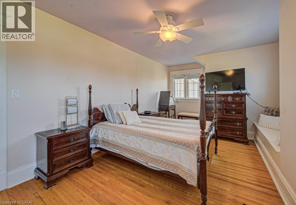 Hardwood flooring throughout featuring a ceiling fan with integrated lighting, a window with horizontal muntins, and a built-in window bench - 2032 Coronation Boulevard, Cambridge, ON - Indoor Photo Showing Bedroom