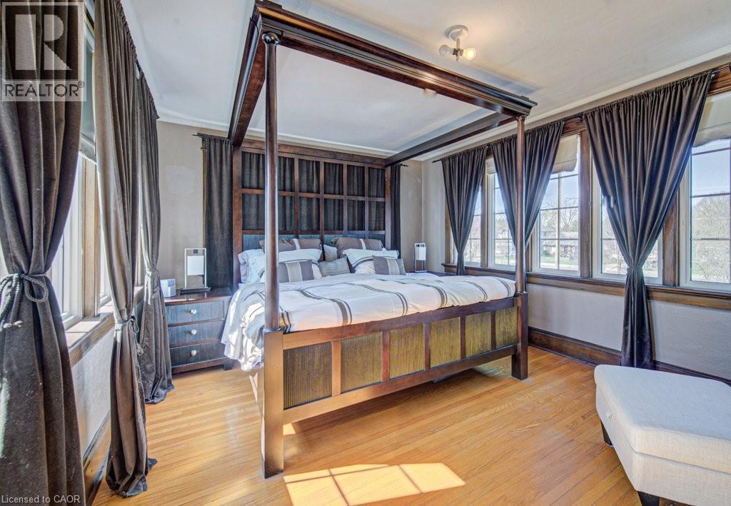 Hardwood flooring and multiple windows with dark trim and dark curtains - 2032 Coronation Boulevard, Cambridge, ON - Indoor Photo Showing Bedroom
