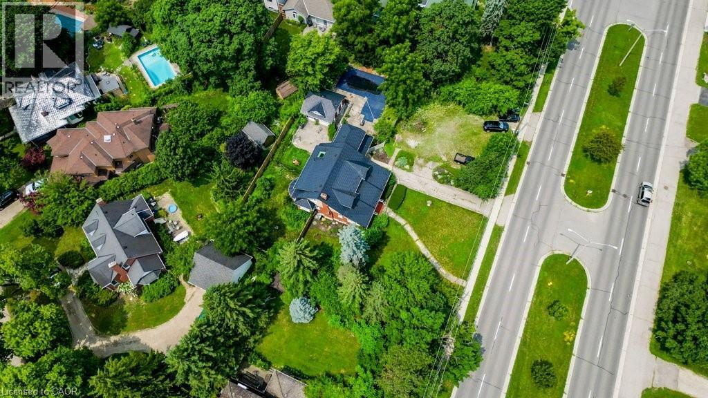 Aerial perspective showcasing a residential property with surrounding mature trees, expansive green spaces, and a paved road - 2032 Coronation Boulevard, Cambridge, ON - Outdoor With View