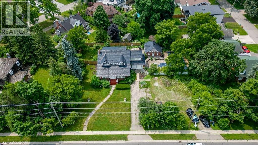 Traditional-style property featuring a prominent red brick facade with dark roof shingles and dormer windows - 2032 Coronation Boulevard, Cambridge, ON - Outdoor