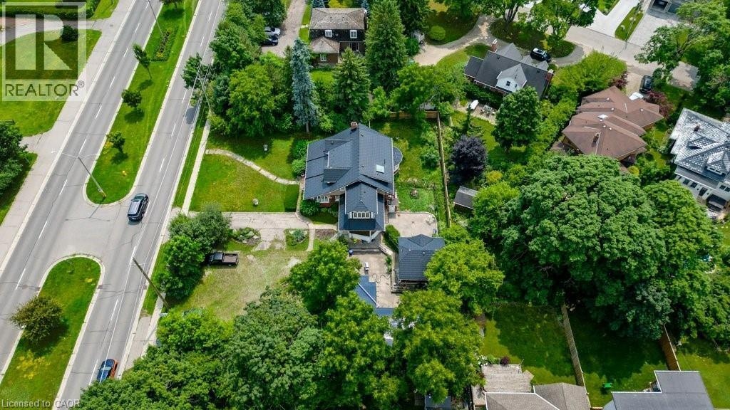 Expansive property featuring a substantial residence with a dark roof, surrounded by mature trees and manicured green spaces - 2032 Coronation Boulevard, Cambridge, ON - Outdoor With View