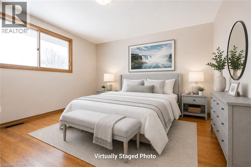 Bedroom featuring wood-finish flooring, a neutral color palette, and a substantial window with wood-finish trim - 66 Summit Avenue, Kitchener, ON - Indoor Photo Showing Bedroom