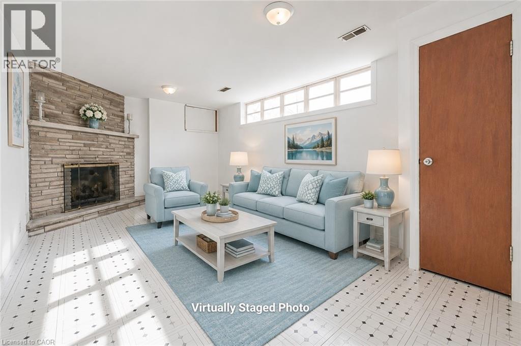 Living area featuring a stone-clad fireplace with a hearth, patterned flooring, and high transom windows - 66 Summit Avenue, Kitchener, ON - Indoor Photo Showing Living Room With Fireplace