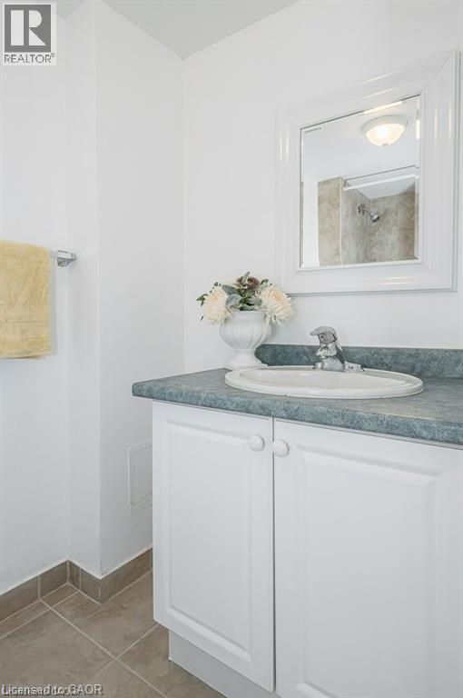 Bathroom vanity featuring a white cabinet, integrated sink, and a framed mirror - 66 Summit Avenue, Kitchener, ON - Indoor Photo Showing Bathroom
