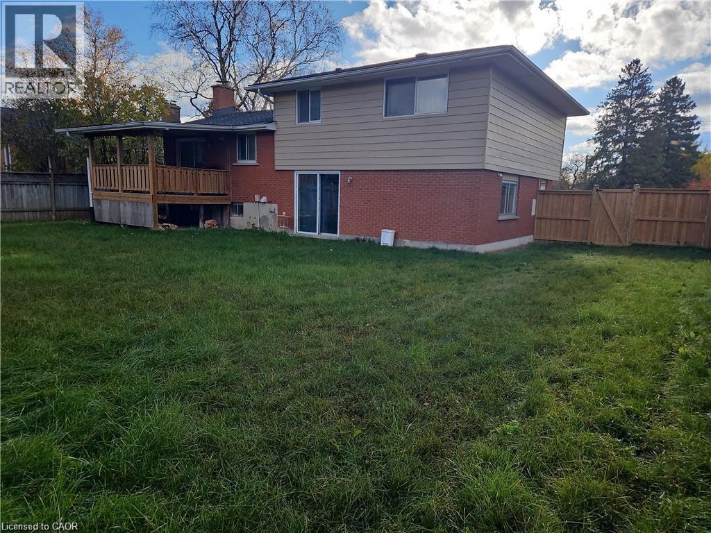 Expansive grassy yard area with a raised wooden deck featuring a covered roof and wooden railings - 66 Summit Avenue, Kitchener, ON - Outdoor