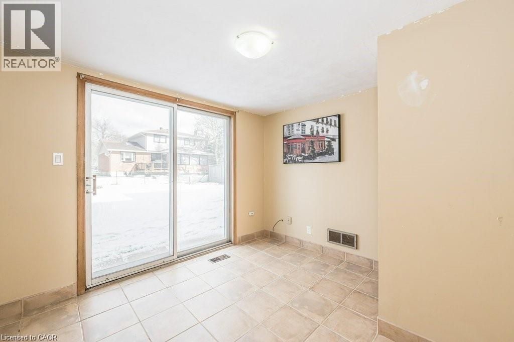 Sliding glass patio doors providing outdoor access, recessed floor vent, and neutral tile flooring with matching base trim - 66 Summit Avenue, Kitchener, ON - Indoor Photo Showing Other Room