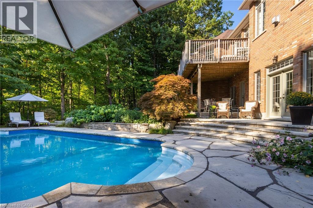In-ground swimming pool featuring curved entry steps and flagstone coping - 1285 Beaufort Drive, Burlington, ON
